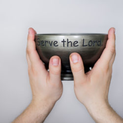 Uplifted hands holding a bowl which says, serve the Lord